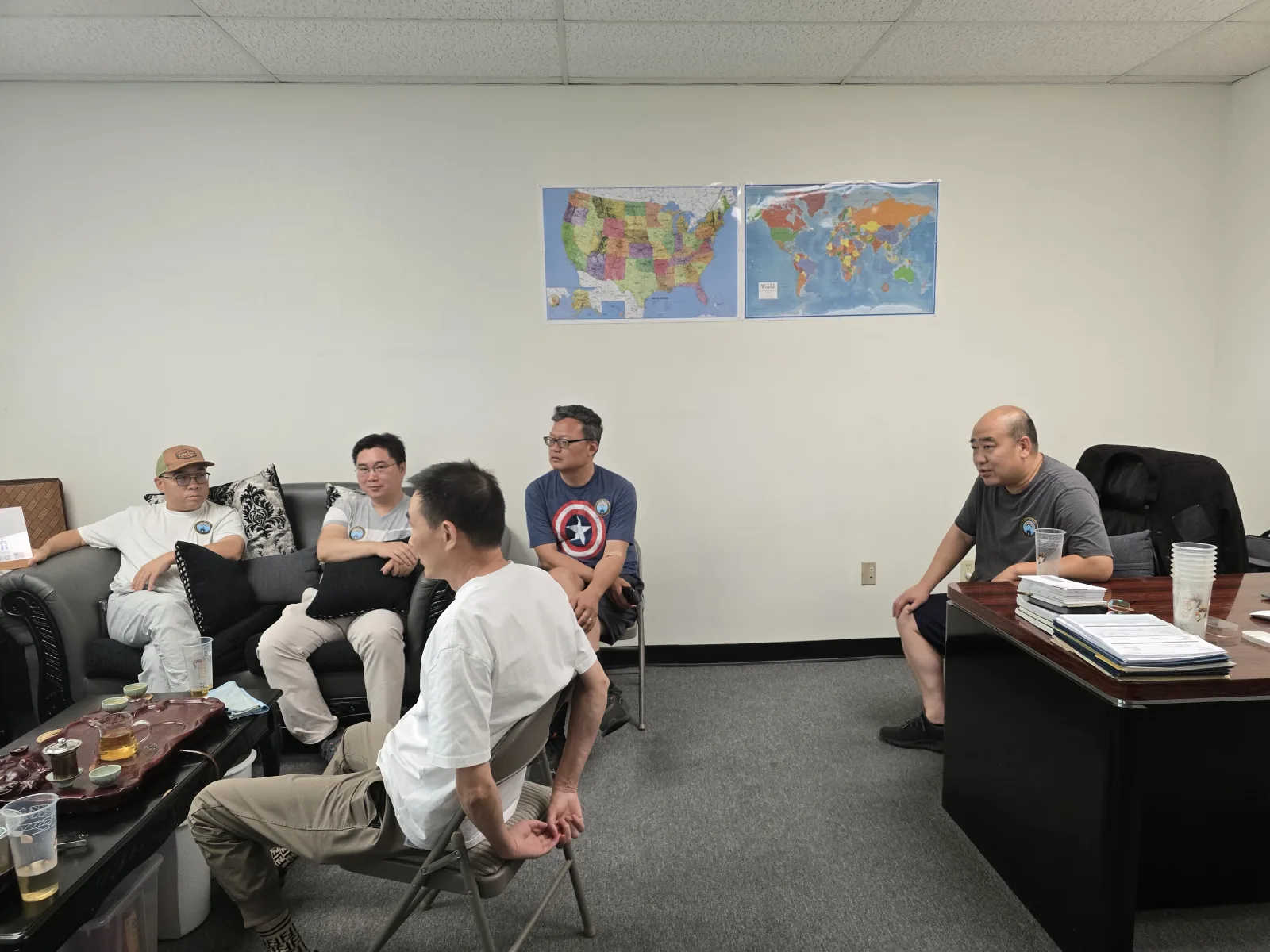 桥友会现场:办公室另一端,办公桌与两幅地图,对面沙发上坐着桥友